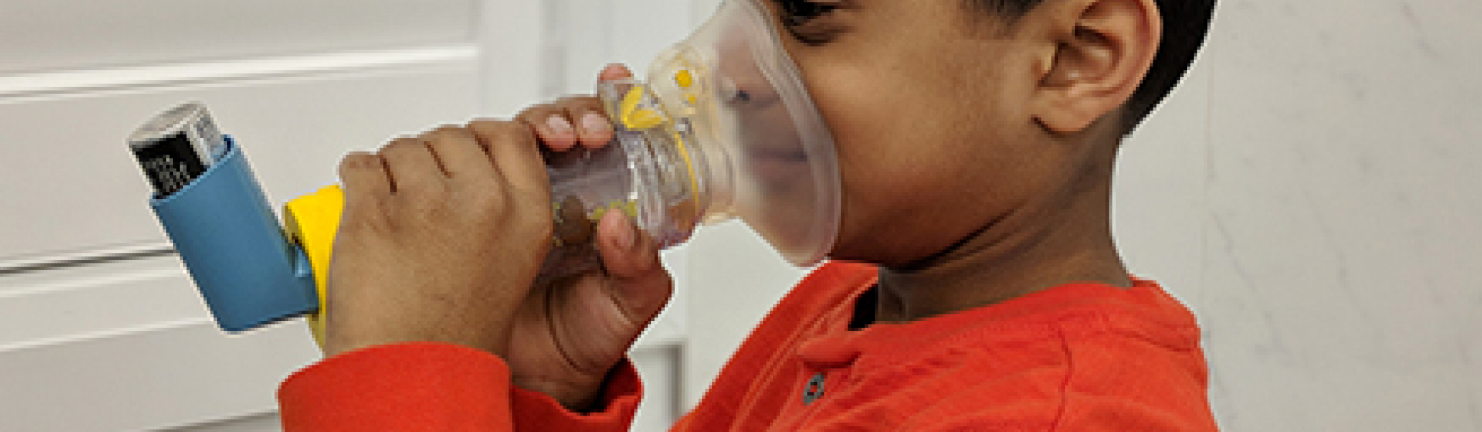 Child using an age-appropriate valved spacer device with an asthma inhaler