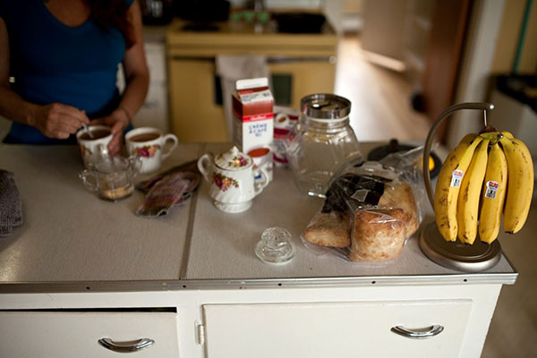 Food on a table as a woman stirs her coffee in a mug