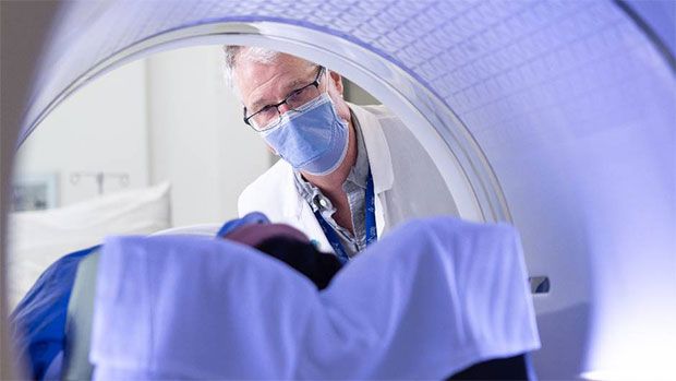 A doctor watches a patient in a PET/CT device