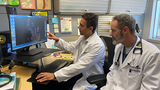 Dr. Saman Maleki and Dr. John Lenehan look at an image of a tumor on a computer screen.
