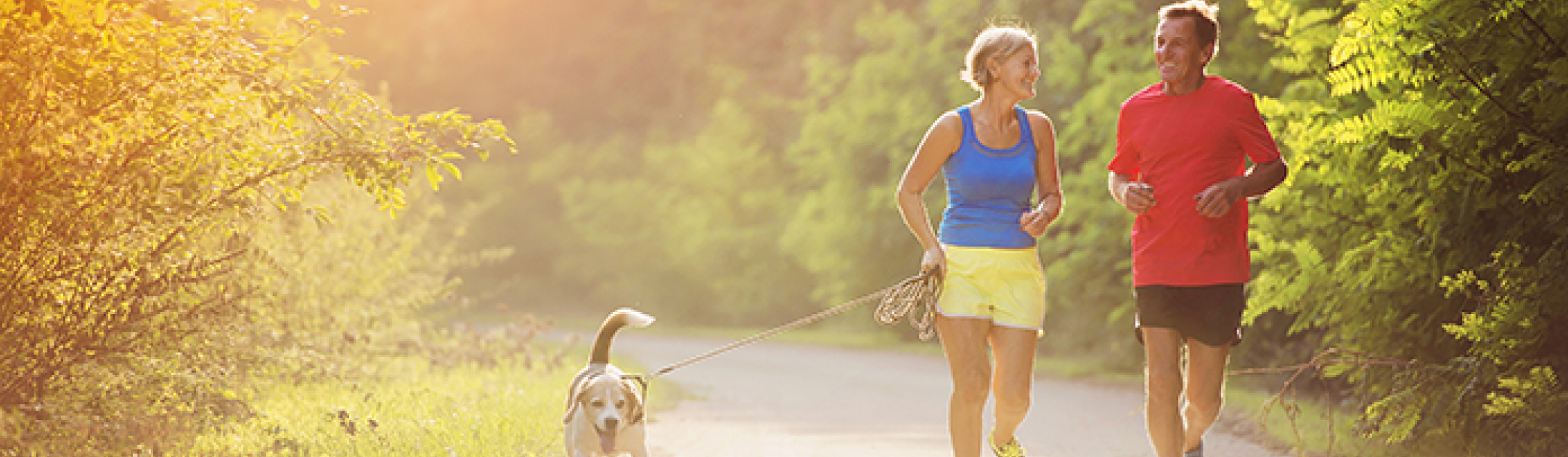 Older couple jogging with their dog